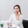 front-view-smiley-woman-posing-with-headset-desk